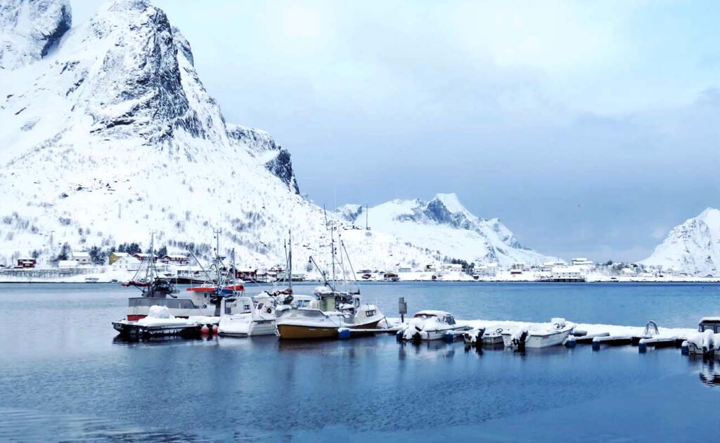 paesaggio con barche e montagne innevate sullo sfondo alle lofoten norvegia