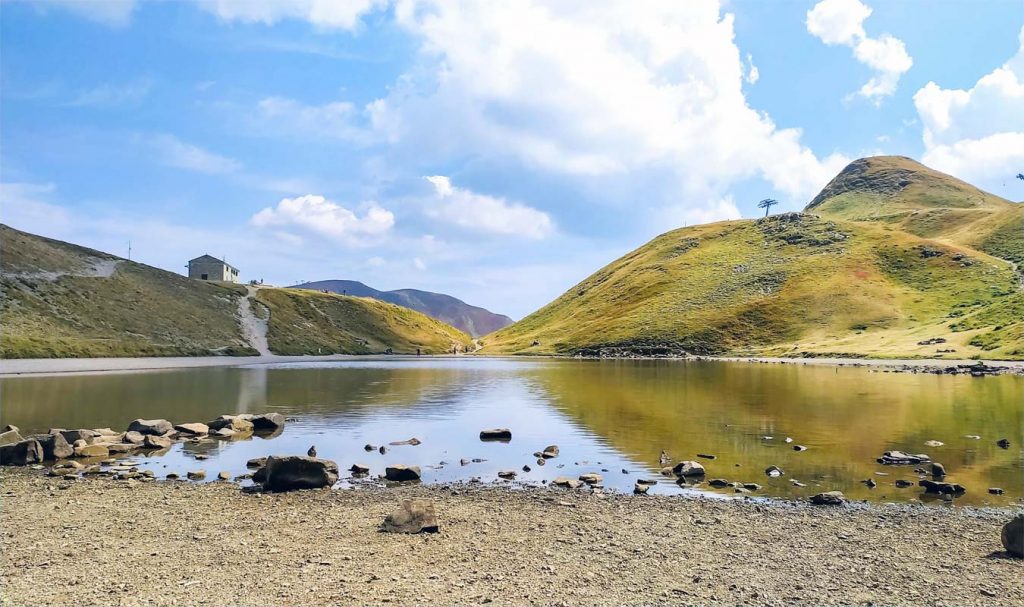 lago scaffaiolo circondato da colline con il rifugio duca degli abruzzi di fronte