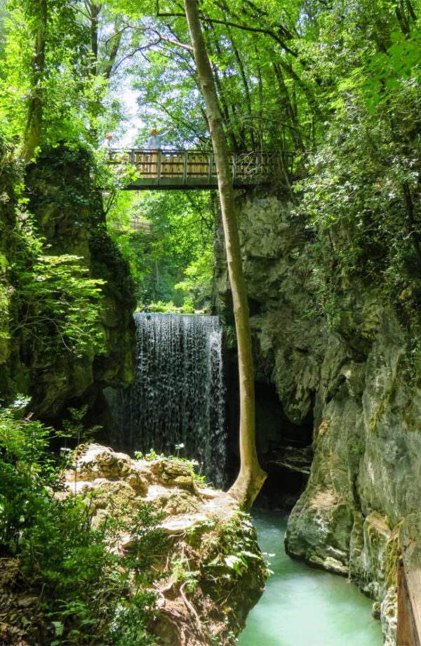 cascata nel bosco con ponte di legno sopra sul sentiero li vurgacci