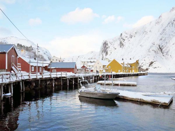 case colorate lungo il mare con le montagne innevate sullo sfondo a nusfjord